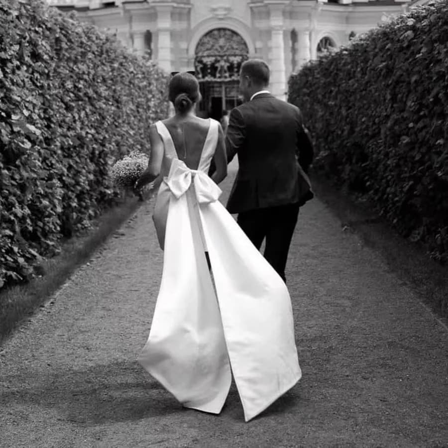 Krátké saténové svatební šaty s výstřihem do V, odhalenými zády a mašlí